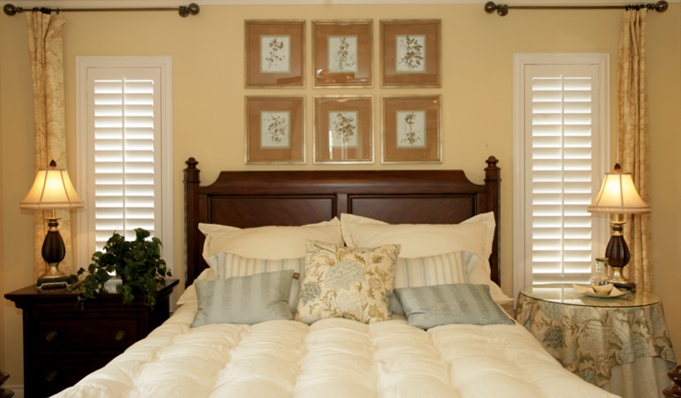 Bedroom with two tall plantation shutters on either side of bed in St. George 